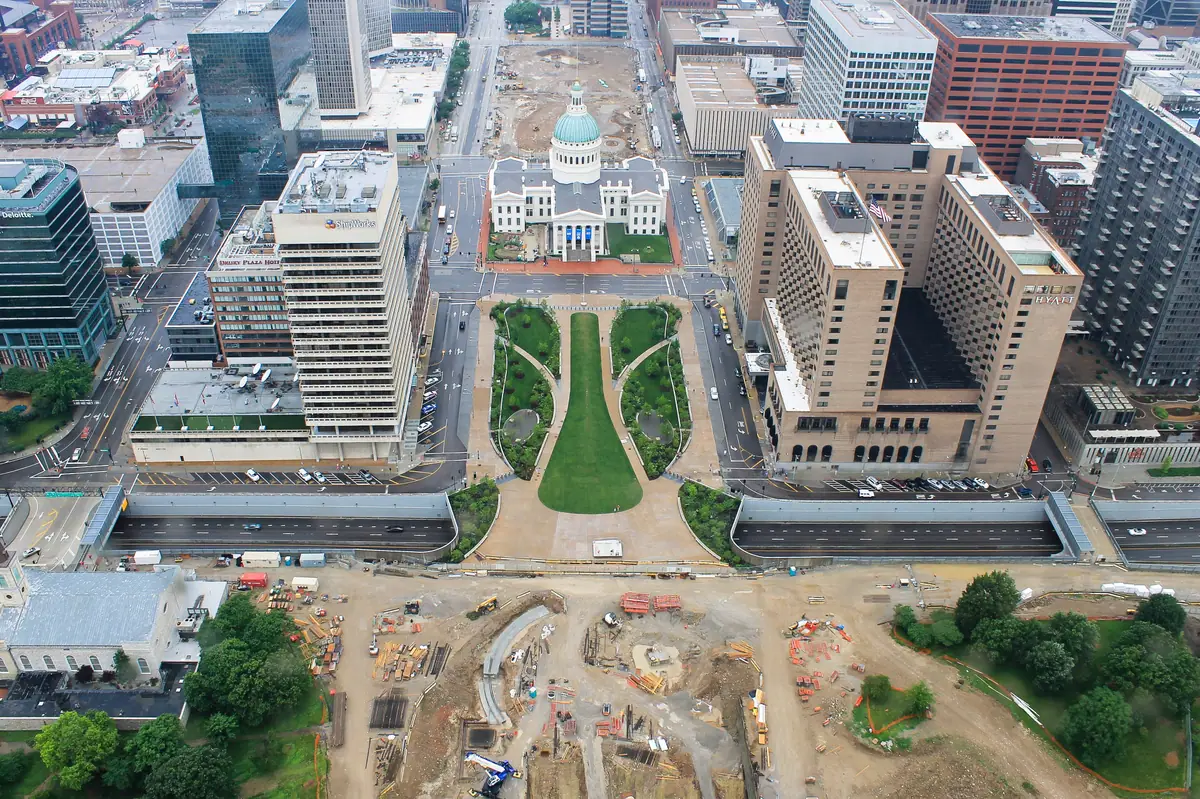 Overhead aerial view of an active construction site with excavation, staging areas and equipment beside downtown buildings
