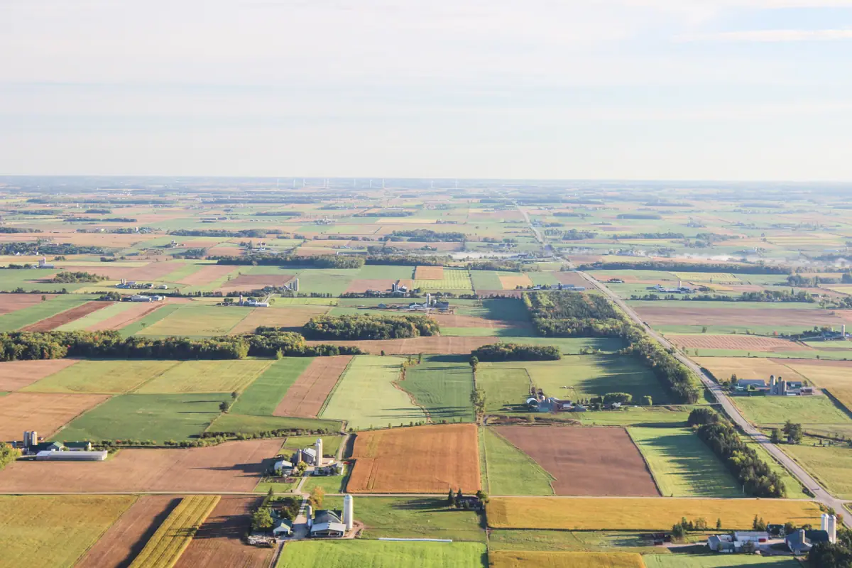 Aerial view of patchwork farm fields, shelterbelts and farmsteads stretching to the horizon