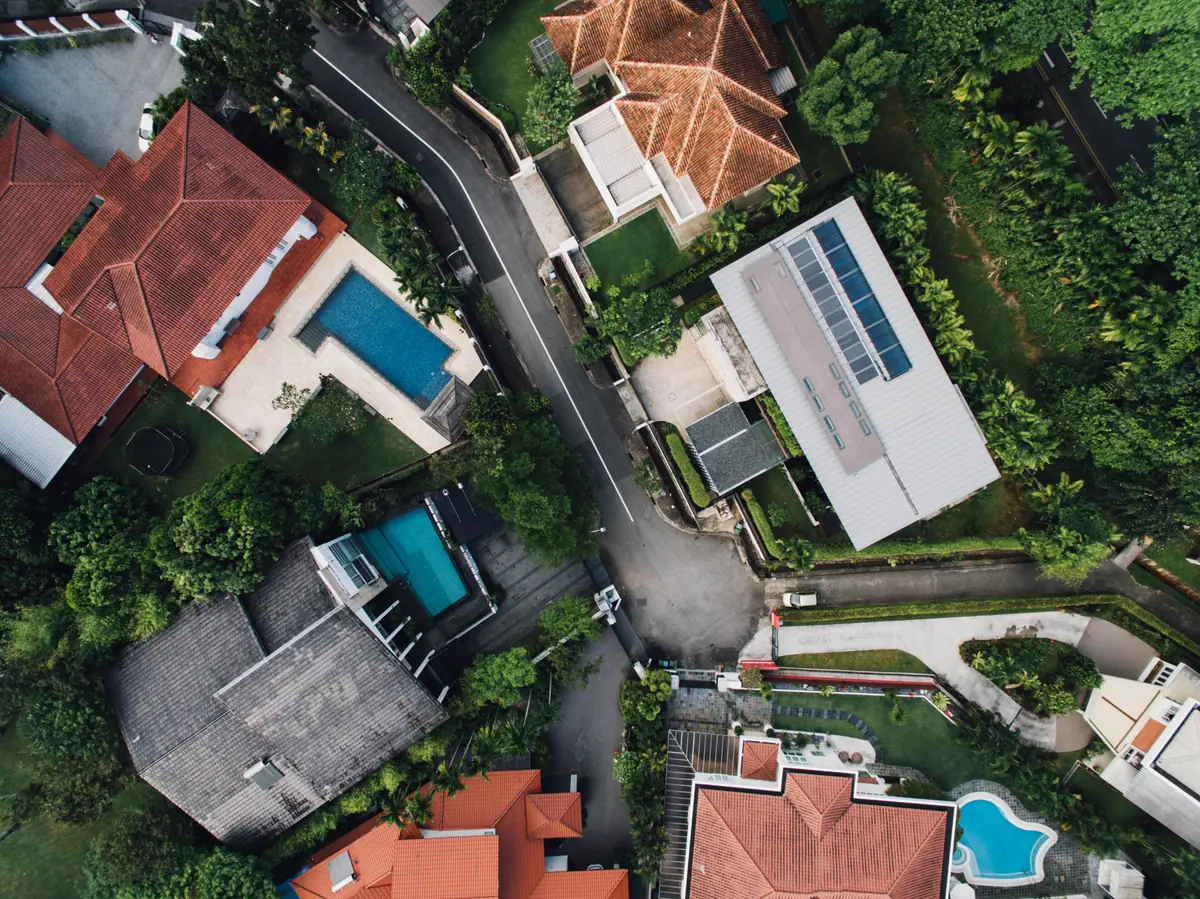 Top-down aerial view of homes with roofs, driveways, pools and landscaping